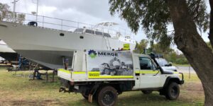 Merge Mechanical service truck parked near a large white boat, indicating the company's versatility beyond just heavy equipment maintenance projects.
