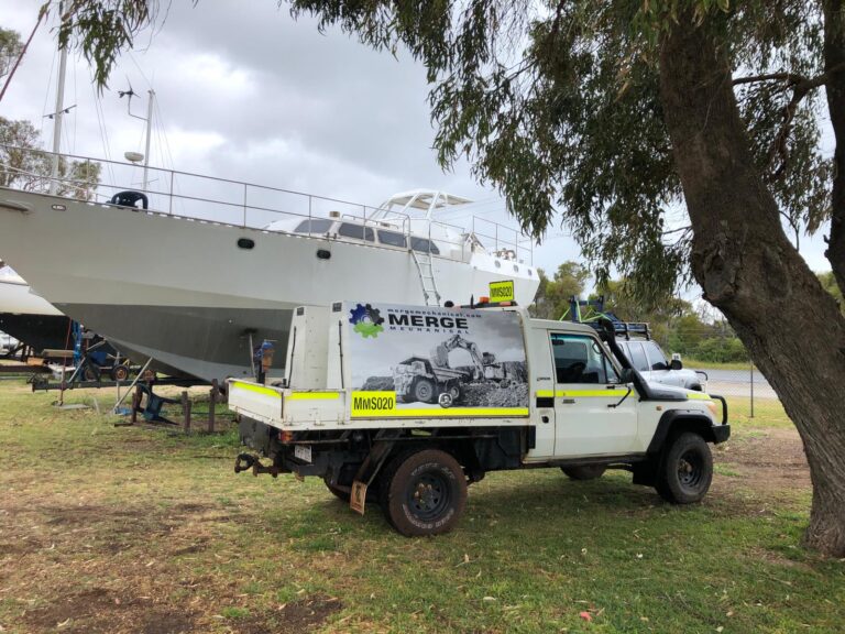 Merge Mechanical service truck parked near a large white boat, indicating the company's versatility beyond just heavy equipment maintenance projects.