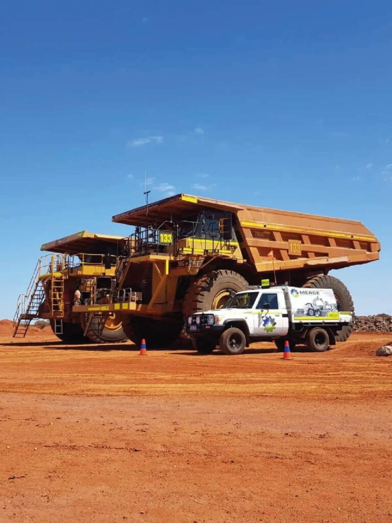 Merge Mechanical service vehicle stationed beside a large haul truck on-site, demonstrating the scale and capability of the company's heavy equipment maintenance operations.